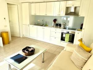a kitchen with white cabinets and a table in a living room at JASMINE DELUXE APARTMENT with super-king bed, large sun terrace and spectacular views in Vis
