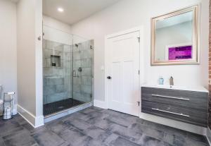 a bathroom with a shower and a sink and a mirror at Chic Downtown Retreat Fireplace Game Area in Hot Springs +41 photos