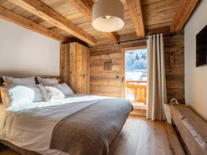 ein Schlafzimmer mit einem Bett und einem großen Fenster in der Unterkunft Demi-chalet moderne 4 chambres + dortoir, terrasse, garage - La Clusaz - FR-1-459-238 in La Clusaz