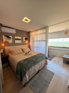 a bedroom with a large bed and a large window at Conforto Frente ao Mar - Areia Preta in Guarapari