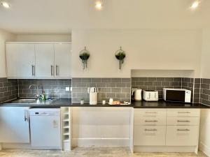 a kitchen with white cabinets and black counter tops at Beachside Haven in Centre with Garden and Parking - 5 Mins Walk to The Beach in Bournemouth