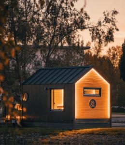 a small house with a black roof in a field at Arctic circle cabin 1 in Rovaniemi