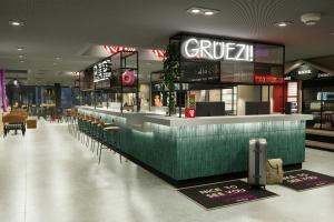 een restaurant met bar en stoelen in een winkelcentrum bij Moxy Zurich in Zürich