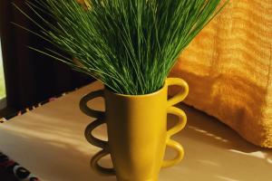 a yellow vase with grass in it on a table at Tiny Huts Camp - Free Massage Hot Tub Sauna Waterfall Nearby in Tulbaghweg