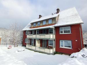 ein rotes Haus mit Schnee auf dem Boden in der Unterkunft Haus Christoffel Wieda in Wieda