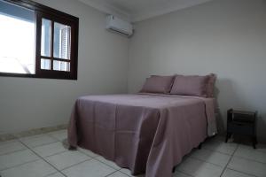 una camera da letto con un letto con una coperta viola e una finestra di Duplex Espaçoso - Praia e Centro - Garagem Fechada e Área Gourmet a Xangri-lá