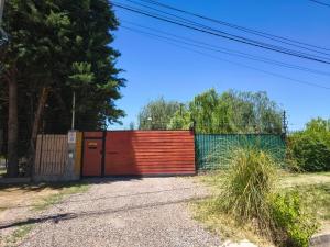 ein roter Zaun mit einer roten Tür an einer Straße in der Unterkunft CasAmigos Cruz de Piedra in Maipú