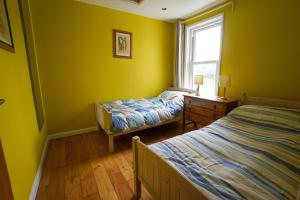 two beds in a room with yellow walls and a window at Charming 2 BDR Home with Garden and Light in London