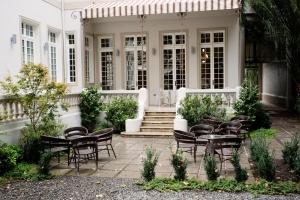 eine Terrasse mit Stühlen und Tischen vor einem weißen Haus in der Unterkunft Matildas Hotel Boutique in Santiago