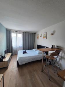 a bedroom with a bed and a desk and a table at Joli studio Disneyland Paris 2 pers in Bussy-Saint-Georges