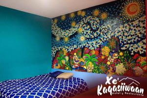 a bedroom with a painting on the wall at Xe 'Gakasiiwaan in San Juan La Laguna