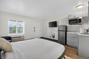 a white bedroom with a bed and a kitchen at Bright modern studio featuring full kitchenette in Las Vegas