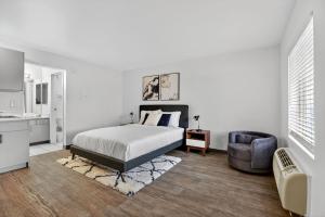 a white bedroom with a bed and a chair at Bright modern studio featuring full kitchenette in Las Vegas