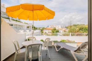 une table et des chaises sur un balcon avec un parasol dans l'établissement Muthu Clube Praia da Oura, à Albufeira