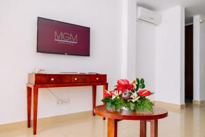 une télévision sur un mur au-dessus d'une table avec un vase de fleurs dans l'établissement Muthu Clube Praia da Oura, à Albufeira