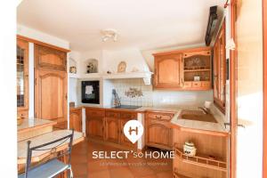 une cuisine avec des armoires en bois et un évier dans l'établissement SELECT'SO HOME - Villa PANORAMA - Services hôteliers & prestations de qualité, au Lavandou
