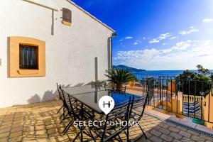 ein Tisch und Stühle auf einer Terrasse mit Blick auf das Meer in der Unterkunft SELECT'SO HOME - Villa PANORAMA - Services hôteliers & prestations de qualité in Le Lavandou