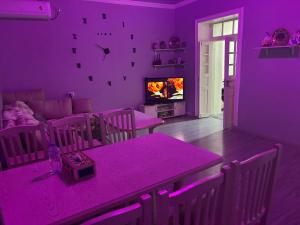 a purple living room with a table and a tv at Домик Zara in Samarkand