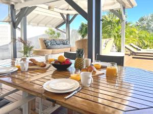 Ein Holztisch mit Essen und Orangen auf einer Terrasse in der Unterkunft Villa Mangorient 3 bd private pool in Orient Bay in Orient Bay