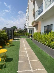 un jardin avec des chaises et des tables ainsi qu'un bâtiment dans l'établissement Belrose Place Studio Apartment, à Accra