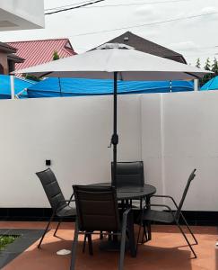 une table et des chaises avec un parasol sur une terrasse dans l'établissement Crescent Cove, Luxury 3 Bedroom Home, à Kwedonu