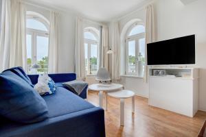 een woonkamer met een blauwe bank en een tv bij Villa Sonneck Appartement 20 in Ostseebad Sellin