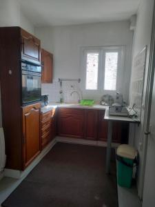 Una cocina con gabinetes de madera, un fregadero y un refrigerador. en L'univers d'Arras, en Arras