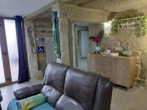 a living room with a leather couch and a counter at Casa Piedra Miranda. in Vilaboa