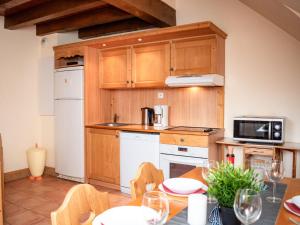 eine Küche mit Holzschränken und einem Tisch mit Stühlen in der Unterkunft Duplex 1 Pièce 6 pers avec Balcons et Parking à Pra Loup - FR-1-504-167 in Uvernet