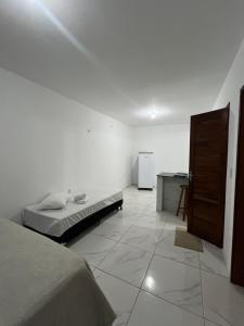 a white room with a bed and a refrigerator at Apartamento da Kenia in Canoa Quebrada