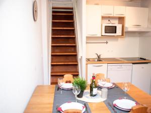 eine Küche und ein Esszimmer mit einem Tisch und Weingläsern in der Unterkunft Charmant Duplex avec Balcon et Piscine - 4 Pers, Vignec, à Proximité de Saint-Lary-Soulan - FR-1-504-277 in Vignec