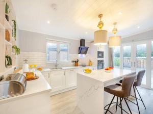 a kitchen with white cabinets and a large island with bar stools at Sandbanks 2 bed Lodge with hot tub - L1 in Brynteg