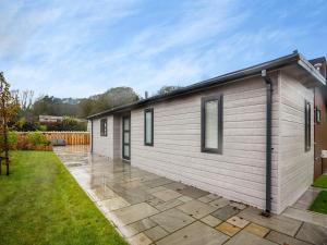 a small white house with a patio at Sandbanks 2 bed Lodge with hot tub - L1 in Brynteg