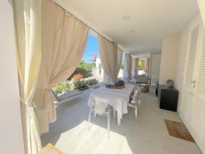 Villa Atusca - Castiglioncello في كاستجليونسيلو: غرفة بيضاء مع طاولة وكراسي ونافذة