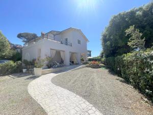 Villa Atusca - Castiglioncello في كاستجليونسيلو: منزل أبيض كبير مع ممر الحصى