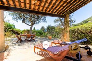 eine Terrasse mit Tisch und Stühlen und einem Baum in der Unterkunft SELECT'SOHOME - Mas des Canadels - Maison pour 6 personnes avec jardin privé ! - RCMAS in Rayol-Canadel-sur-Mer