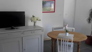 un salon avec une table et une télévision, et une table à manger dans l'établissement Gite Les Jardins d'Harmonie, à Bourgneuf