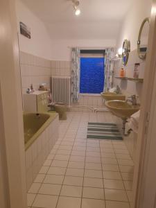 Un baño con una bañera verde y dos lavabos y una ventana. en Zimmer mit Stall, en Geestland