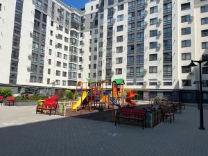 a playground with chairs and a slide in front of tall buildings at Apartament Chișinău centru in Chişinău