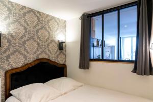 ein Schlafzimmer mit einem Bett und einem Fenster in der Unterkunft Le charme de la place Saint-Sauveur in Caen
