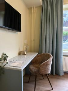 a desk with a chair and a television on a wall at Hotel Atlas Vondelpark in Amsterdam