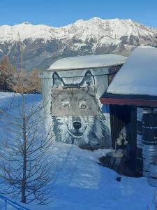 une fresque d'un loup sur le côté d'un bâtiment dans l'établissement Chalet 126 m² PRALOUP, à Uvernet