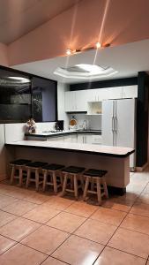 une cuisine avec des armoires blanches et un comptoir avec des tabourets dans l'établissement Quinta La Vita Turrubares, à San Juan de Mata