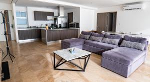 un salon avec un canapé violet et une table dans l'établissement Departamento para 12 personas con vista al mar, à Acapulco