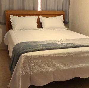 uma cama grande com lençóis e travesseiros brancos em Hospedagem cama e café em Domingos Martins