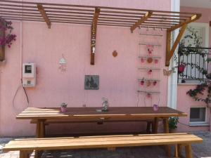a wooden picnic table in front of a pink wall at Elpida Studio in Trapezaki