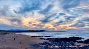 Menschen gehen am Strand unter einem wolkigen Himmel in der Unterkunft Villa Laura in Boó de Piélagos