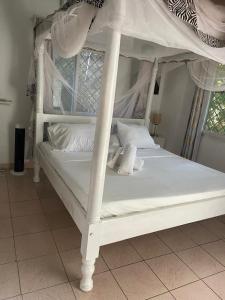 a white canopy bed with white pillows on it at Garner house watamu in Watamu