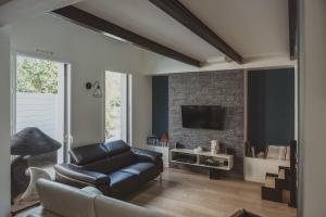 a living room with a leather couch and a tv at 9 pers 160 M² +jardin- 10mn Nantes -30mn mer in Bouguenais