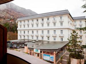 a large white hotel with a building in the foreground at Studio rénové 4 pers avec balcon, wifi, proche télécabine et spa - Brides-les-Bains - FR-1-512-160 in Brides-les-Bains +11 photos